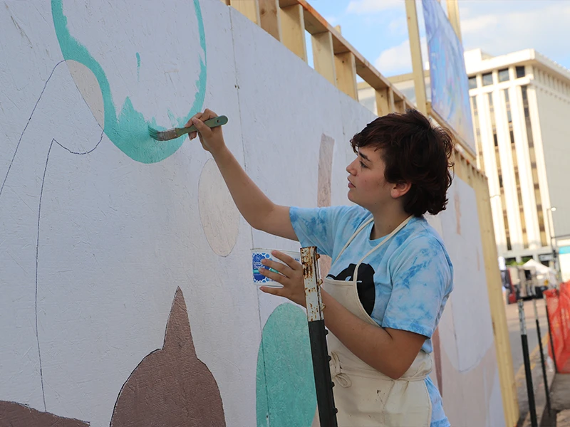 A participant painting a portion of the mural wall.