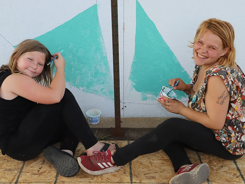 Two participants painting a portion of the mural wall.