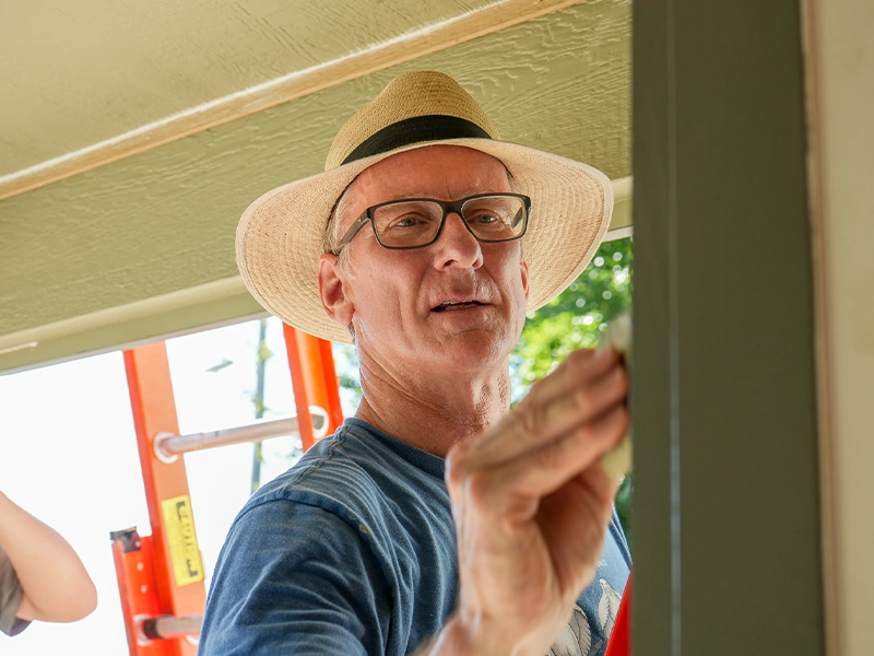A volunteer painting a door frame.