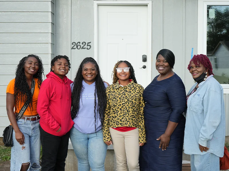 Family partner Victoria and her family in front of a house.