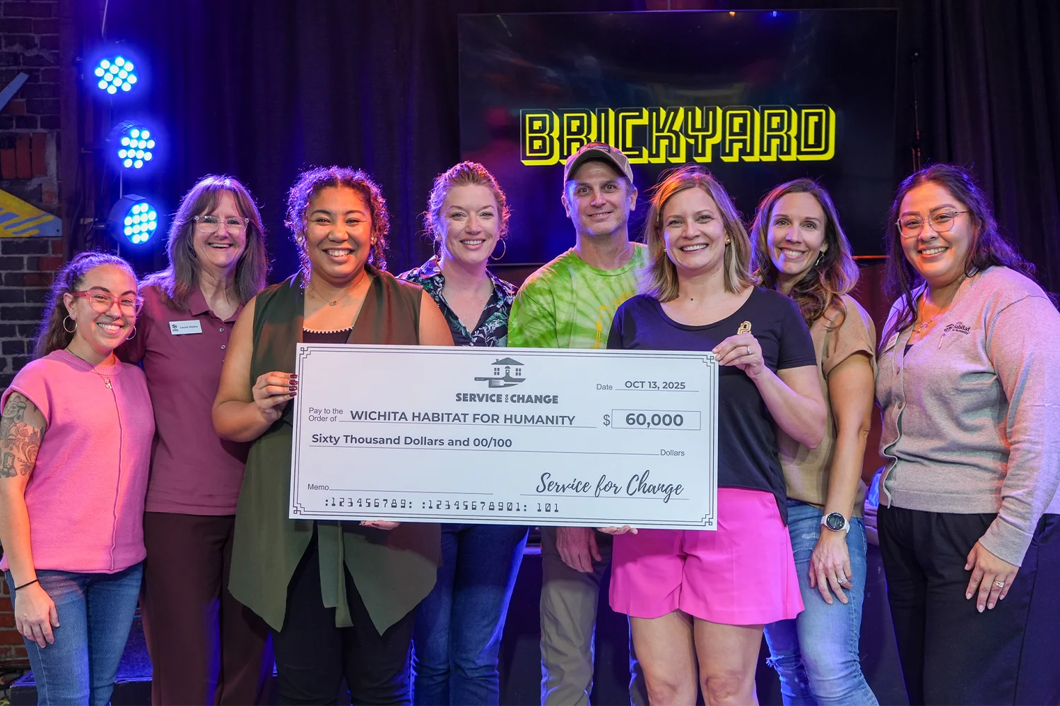 Habitat team members holding a large check for Service for Change.