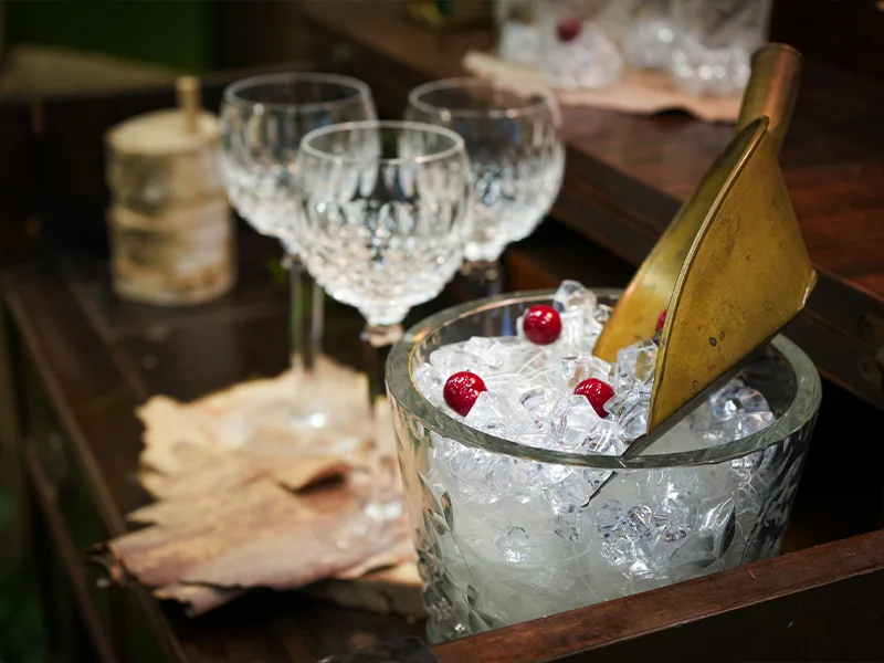 A display of a vintage ice bucket and glassware.