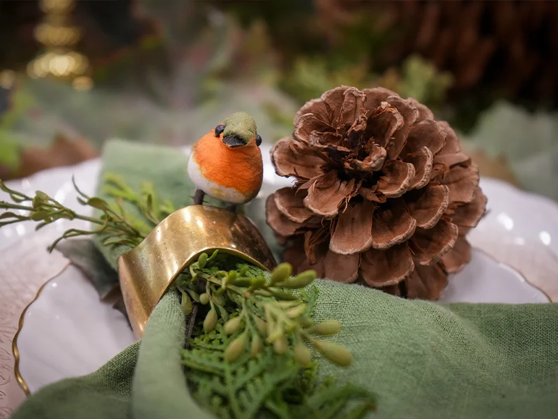 A bird on a decorated handkerchief with pinecone.